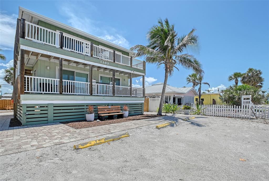 A two-story house with green siding and white railings sits next to a palm tree — 1103 SHORE VIEW DRIVE, ENGLEWOOD, FL
