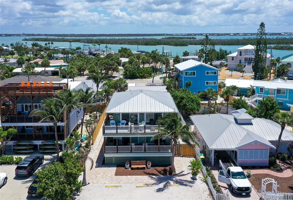 An aerial view shows a multi-story house with a metal roof and surrounding coastal properties — 1103 SHORE VIEW DRIVE, ENGLEWOOD, FL