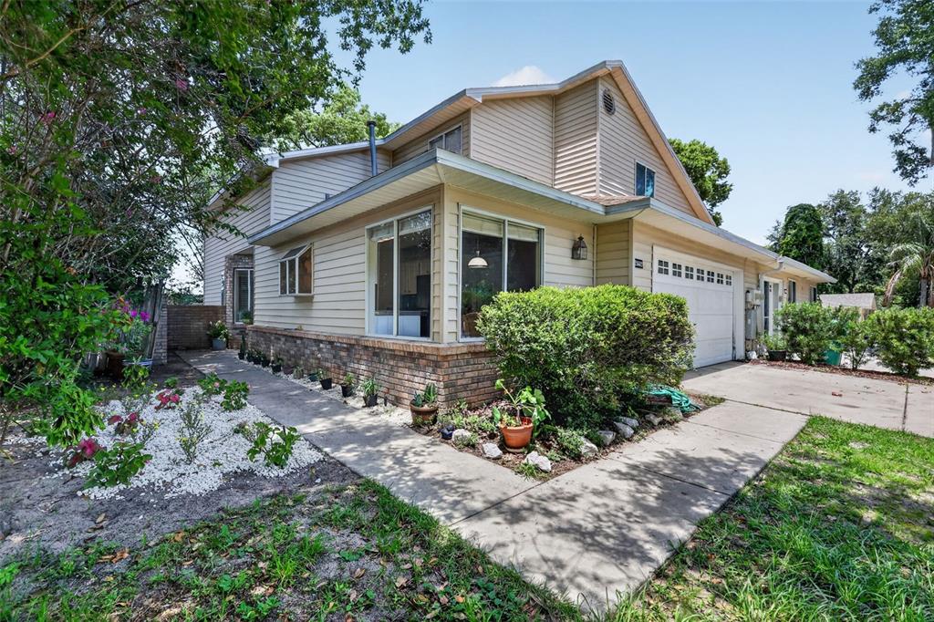 A two-story house with tan siding, a brick base, and a concrete driveway — 2662 MCDONALD TERRACE, MOUNT DORA, FL