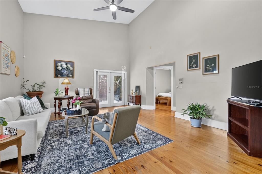 A living room features high ceilings, hardwood floors, a large area rug, and glass doors — 2662 MCDONALD TERRACE, MOUNT DORA, FL