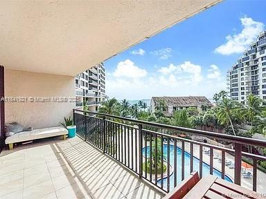 A balcony with a daybed overlooks a swimming pool, palm trees, and a distant bay — 540 Brickell Key Dr # 603, Miami FL 33131, MIAMI, FL