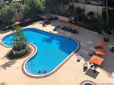 An aerial view shows a curved swimming pool surrounded by lounge chairs and orange umbrellas — 540 Brickell Key Dr # 603, Miami FL 33131, MIAMI, FL