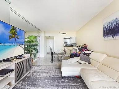 A living room features a white sectional sofa, a television on a console, and dining area — 540 Brickell Key Dr # 603, Miami FL 33131, MIAMI, FL