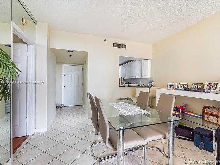 A dining area features a glass table with beige chairs and a view into the kitchen — 540 Brickell Key Dr # 603, Miami FL 33131, MIAMI, FL