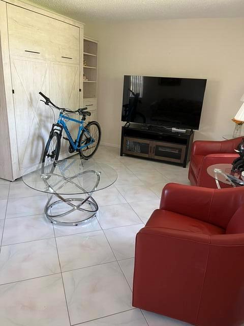 A living room features a wall bed, a blue bicycle, red armchairs, and tile flooring — 457 Flanders # 457, Delray Beach FL 33484, DELRAY BEACH, FL