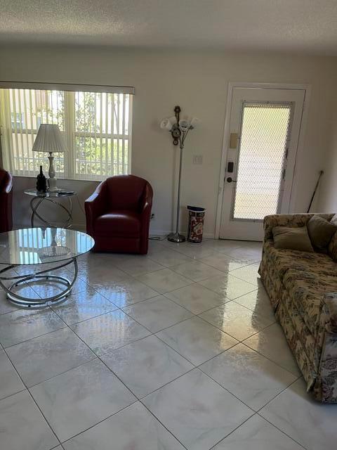 A living room features light-colored tile flooring, a glass coffee table, and a red armchair — 457 Flanders # 457, Delray Beach FL 33484, DELRAY BEACH, FL