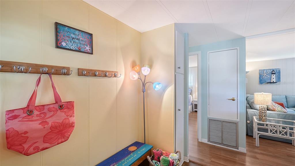 A hallway features a coat rack, a colorful floor lamp, and a pink floral tote bag — 49 CABALLO WAY, BRADENTON, FL