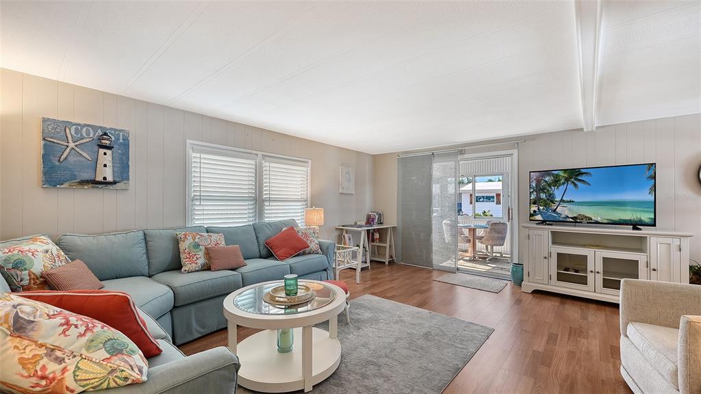 A living room features a blue sectional sofa, a coffee table, and a television console — 49 CABALLO WAY, BRADENTON, FL