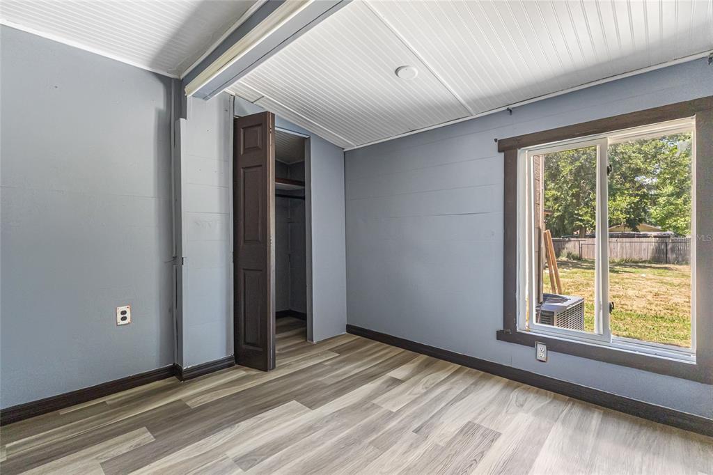 A bedroom with gray walls, wood-look flooring, a closet, and a window overlooking a yard — 517 OAK STREET, AUBURNDALE, FL