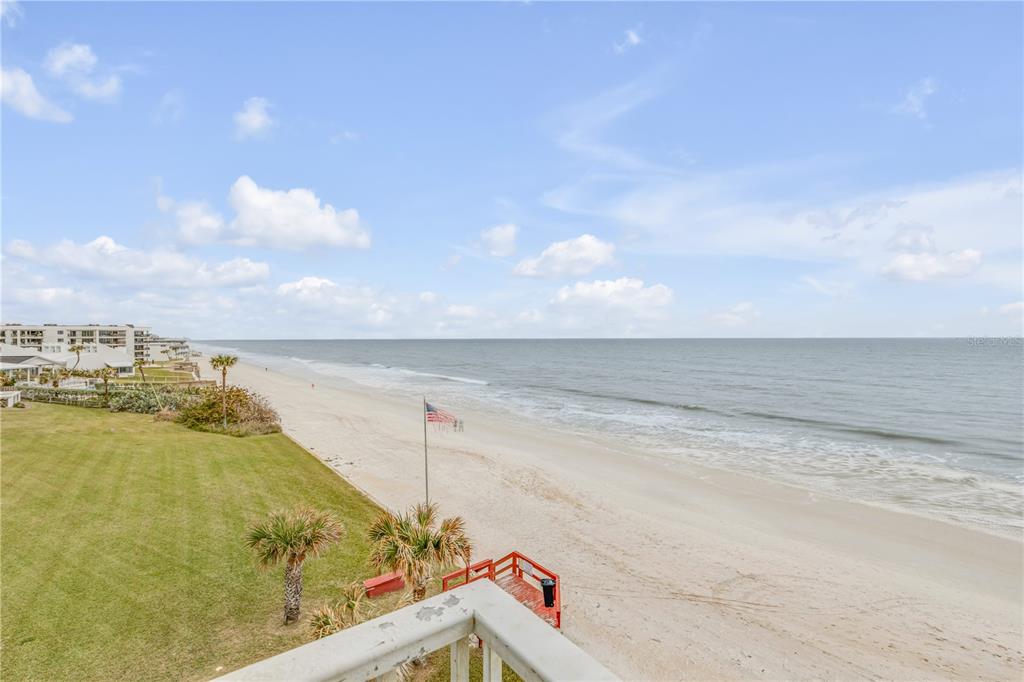 An elevated view of a sandy beach, grassy lawn, and ocean from a balcony — 5203 S ATLANTIC AVENUE UNIT 412B, NEW SMYRNA BEACH, FL