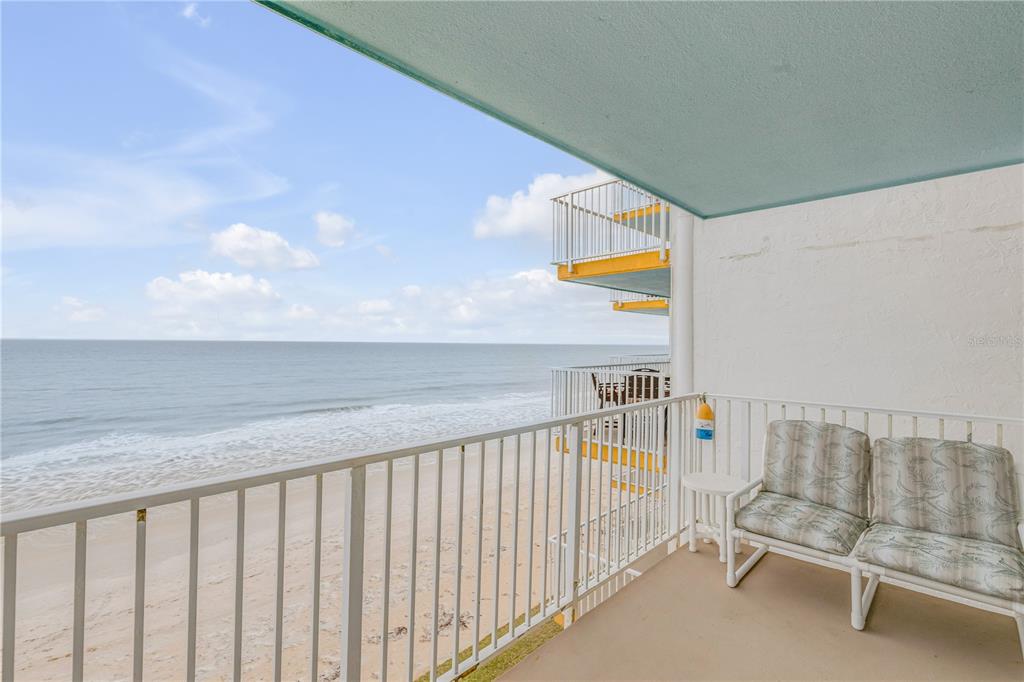 A balcony with white railings overlooks the ocean and sandy beach with two chairs — 5203 S ATLANTIC AVENUE UNIT 412B, NEW SMYRNA BEACH, FL