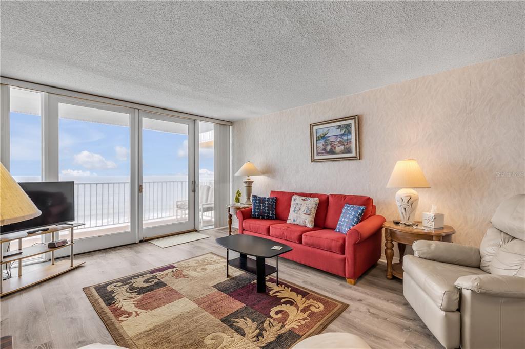 A living room features a red sofa, a beige recliner, and a sliding glass door balcony — 5203 S ATLANTIC AVENUE UNIT 412B, NEW SMYRNA BEACH, FL