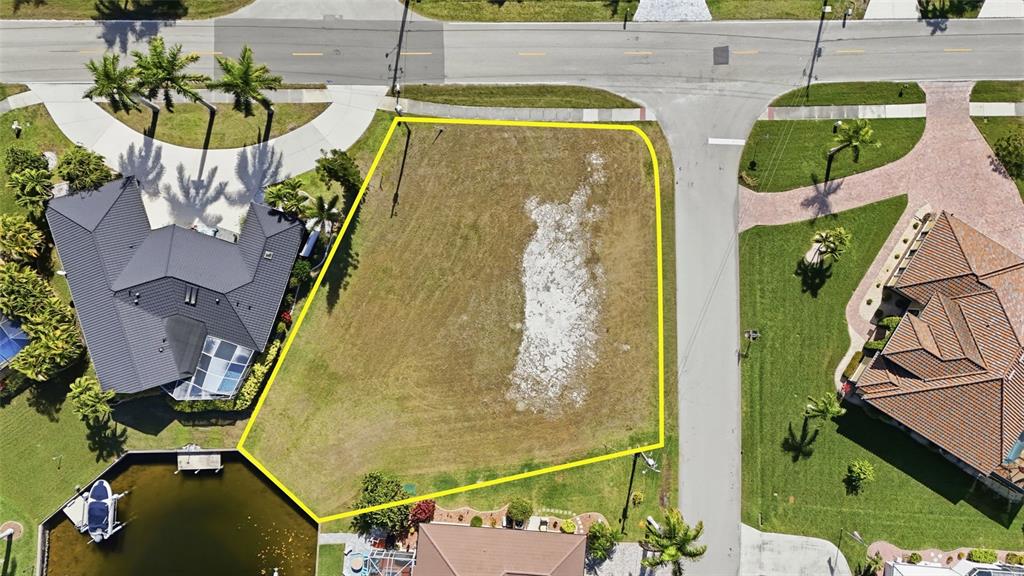 An aerial view shows a vacant, irregularly shaped residential lot bordered by houses and water — 3460 OWL COURT, PUNTA GORDA, FL
