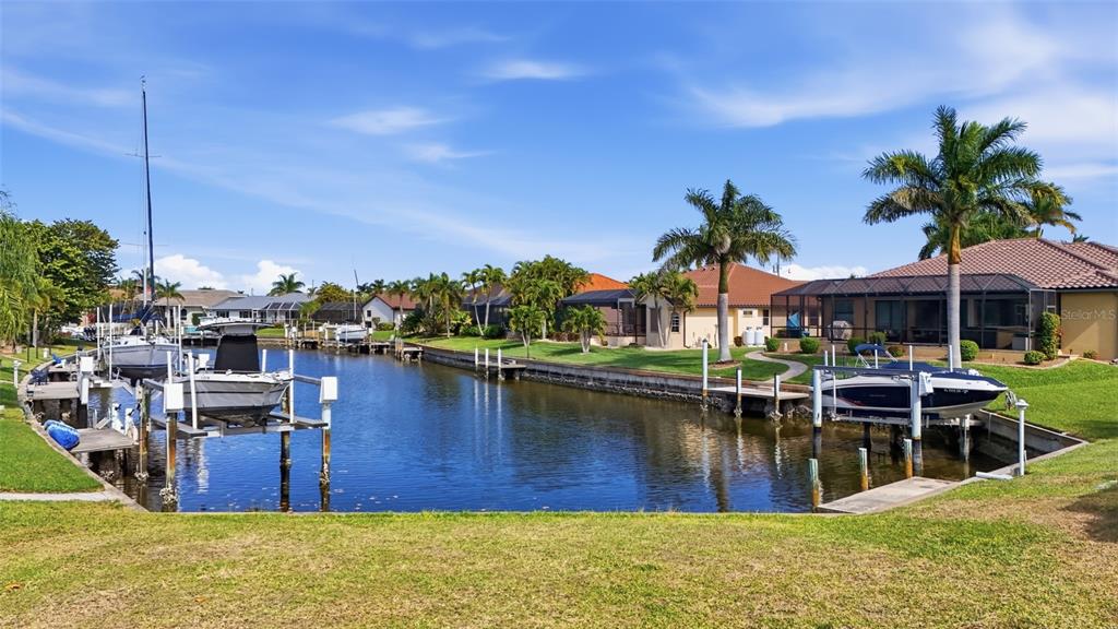 A canal view showing boat lifts, docked boats, palm trees, and waterfront residential homes — 3460 OWL COURT, PUNTA GORDA, FL