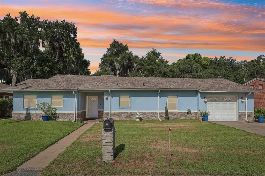 A single-story blue house with stone veneer siding, a white garage door, and a lawn — 31929 ELIZABETH LANE, TAVARES, FL
