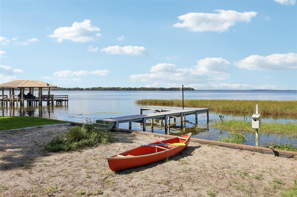 A red canoe sits on a sandy shore near a wooden dock and boat house — 31929 ELIZABETH LANE, TAVARES, FL