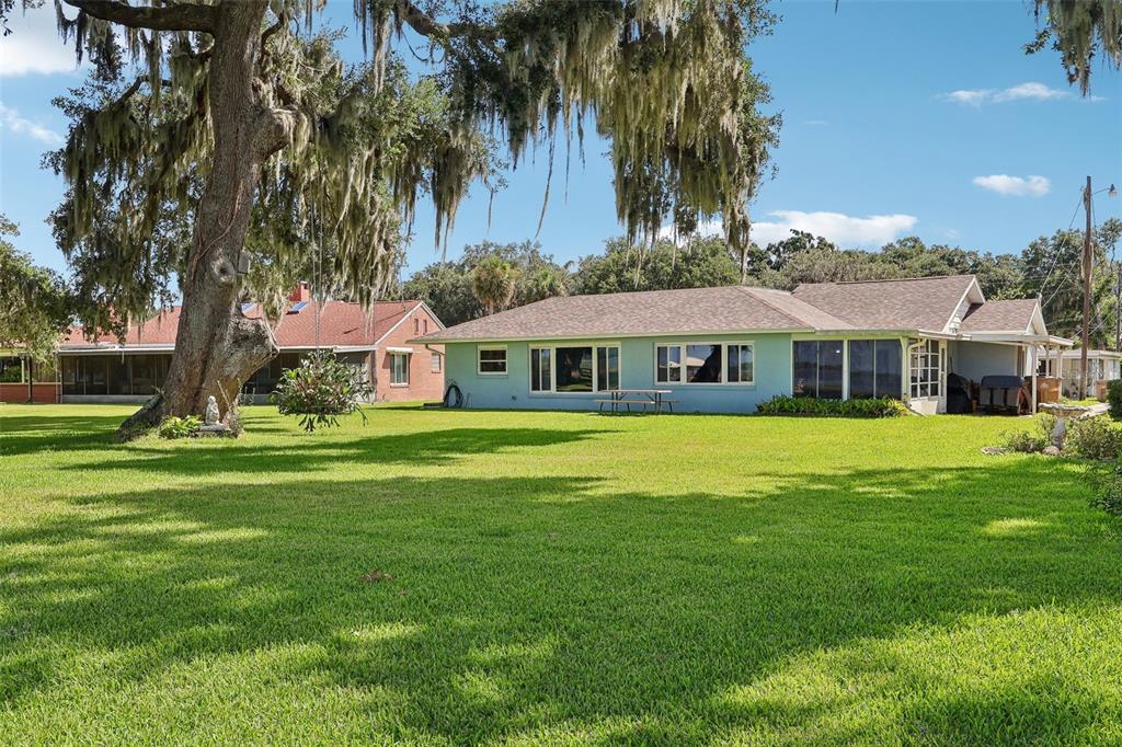 A light blue house with a large lawn and a prominent oak tree with moss — 31929 ELIZABETH LANE, TAVARES, FL