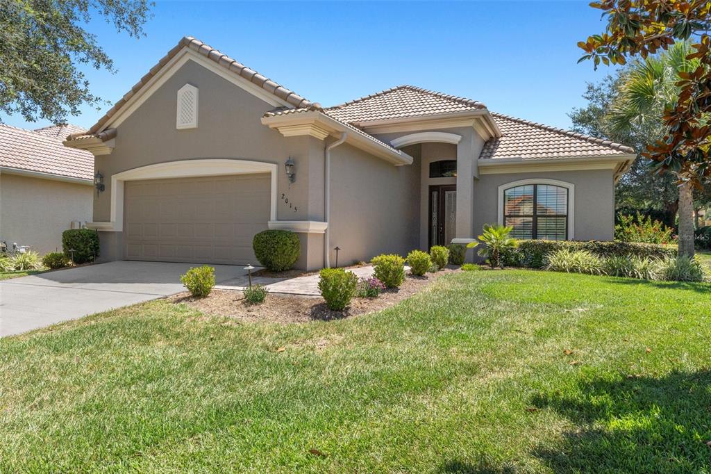 A single-story house with a beige stucco exterior, a tile roof, and a two-car garage — 2015 N RHODES POINT, HERNANDO, FL