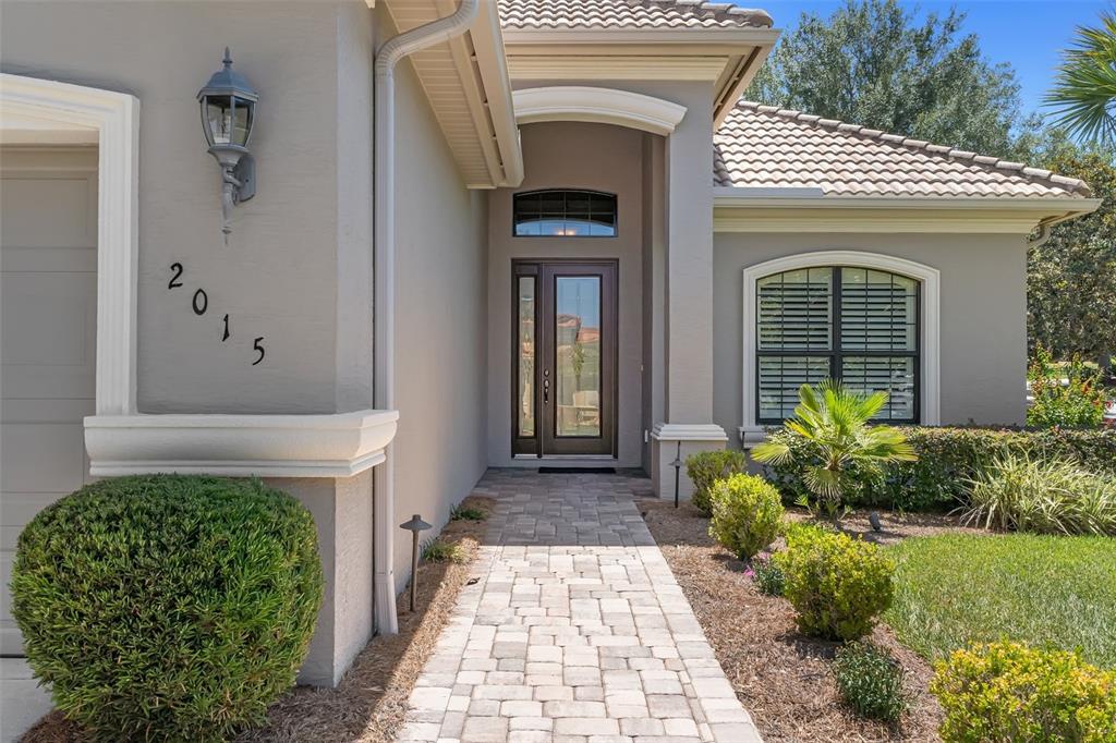 A stone walkway leads to the front entrance of a house with a gray exterior — 2015 N RHODES POINT, HERNANDO, FL