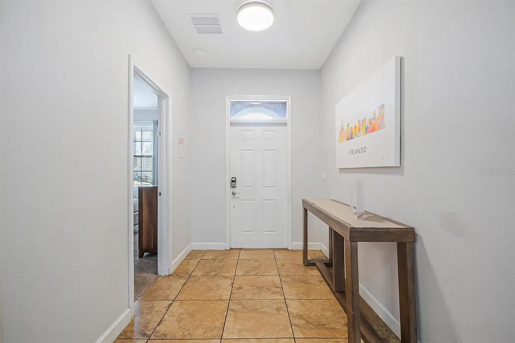 An entryway features a white front door, tiled flooring, and a console table against the wall — 1433 THUNDERBIRD ROAD, DAVENPORT, FL