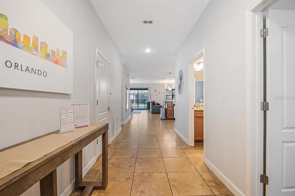A tiled hallway leads from an entryway past a bathroom toward an open living area — 1433 THUNDERBIRD ROAD, DAVENPORT, FL