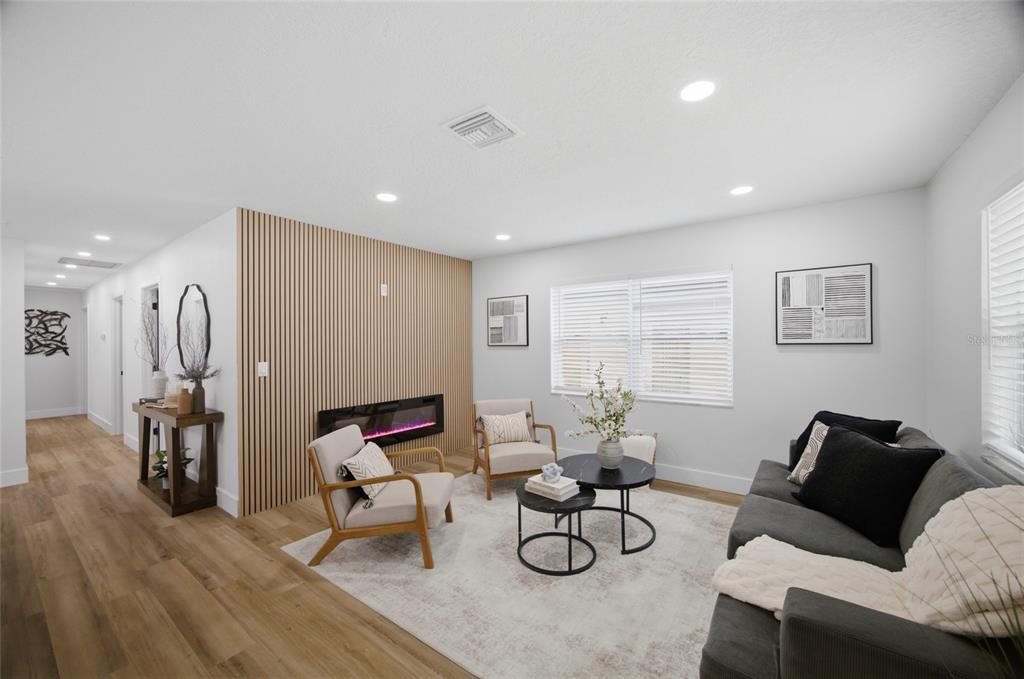A living room features a wood-slat accent wall with an electric fireplace and light flooring — 1001 CARLTON STREET, CLEARWATER, FL