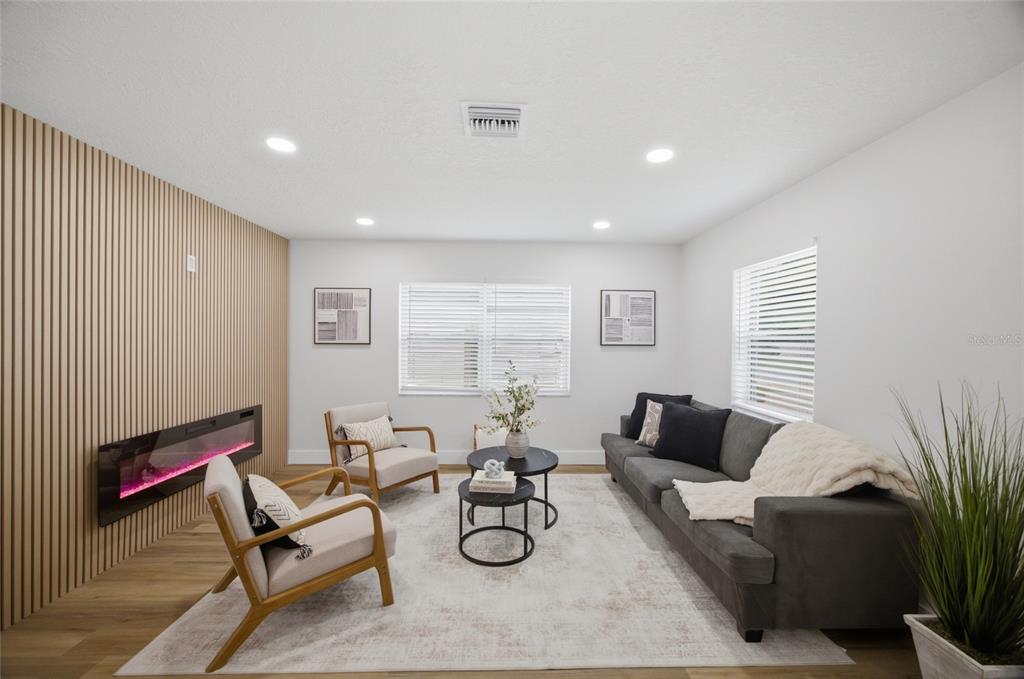 A living room features a slatted wood accent wall, an electric fireplace, and gray furniture — 1001 CARLTON STREET, CLEARWATER, FL