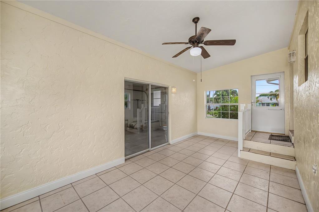 A sunroom with beige textured walls, light tile flooring, a ceiling fan, and sliding doors — 2828 MAGNOLIA WAY, PUNTA GORDA, FL