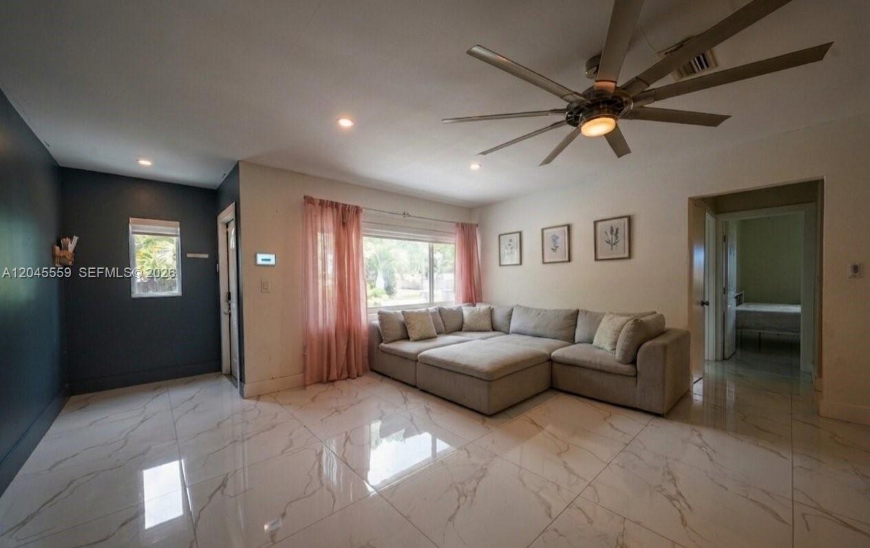 A living room features a large sectional sofa, white marble-style flooring, and a ceiling fan — 7304 Mckinley St, Hollywood FL 33024, HOLLYWOOD, FL
