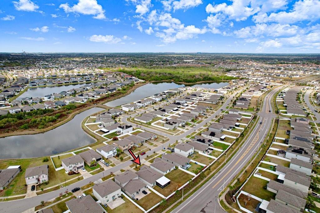 An aerial view shows a suburban neighborhood with a red arrow pointing to a house — 13630 WILD GINGER STREET, RIVERVIEW, FL