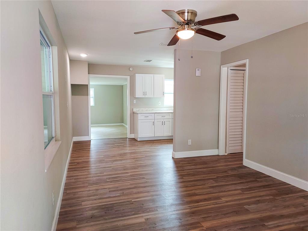 An interior view shows a living area with wood-look flooring, a ceiling fan, and a kitchen — 803 VALENCIA ROAD, PLANT CITY, FL