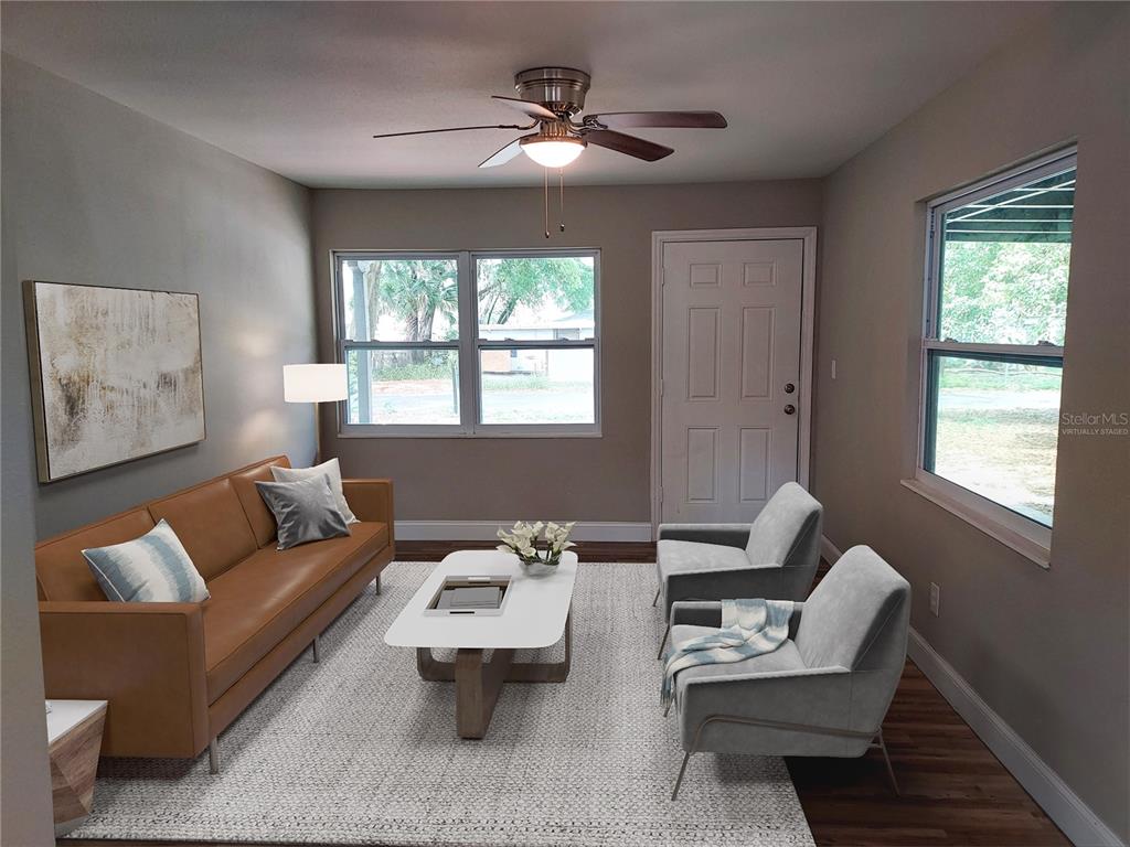 This virtually staged living room features a leather sofa, two armchairs, and a coffee table — 803 VALENCIA ROAD, PLANT CITY, FL