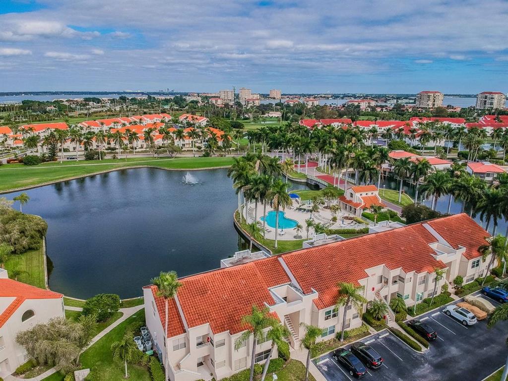 An aerial view of a residential complex with red-tiled roofs, a lake, and a pool — 6050 BAHIA DEL MAR CIRCLE UNIT 120, ST PETERSBURG, FL