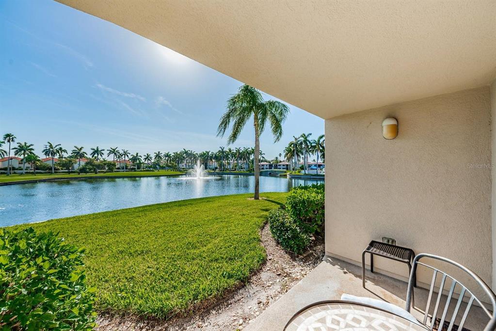 A covered patio overlooks a grassy lawn, a pond with a fountain, and palm trees — 6050 BAHIA DEL MAR CIRCLE UNIT 120, ST PETERSBURG, FL