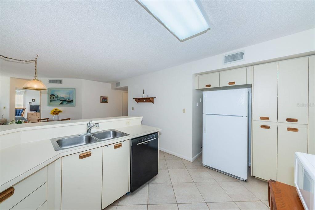 A kitchen with white cabinets, a black dishwasher, a white refrigerator, and tiled flooring — 6050 BAHIA DEL MAR CIRCLE UNIT 120, ST PETERSBURG, FL