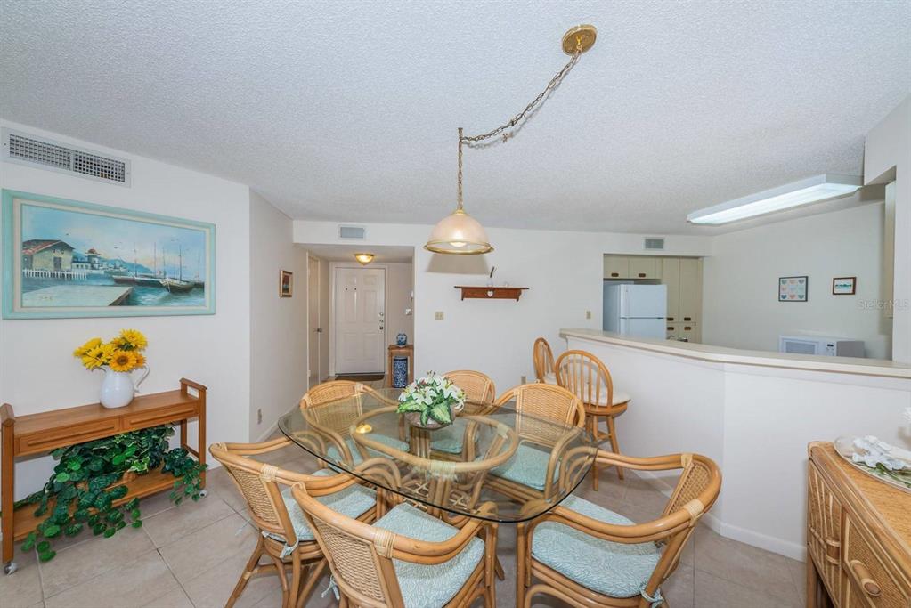 A dining area features a glass-topped table with wicker chairs and a pendant light — 6050 BAHIA DEL MAR CIRCLE UNIT 120, ST PETERSBURG, FL