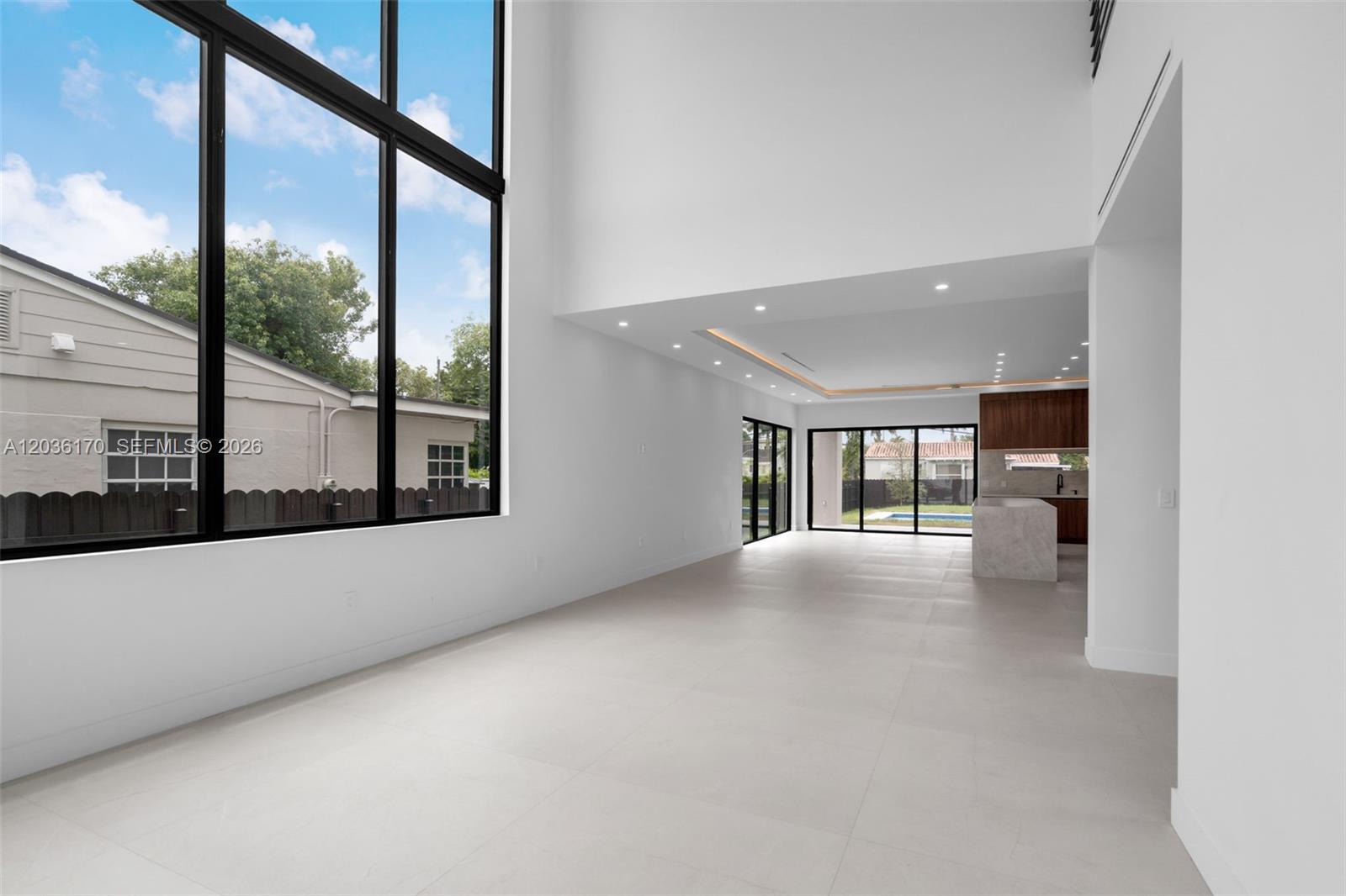 A bright, minimalist living area features high ceilings, large windows, and a modern kitchen — 6438 SW 23rd St, Miami FL 33155, MIAMI, FL