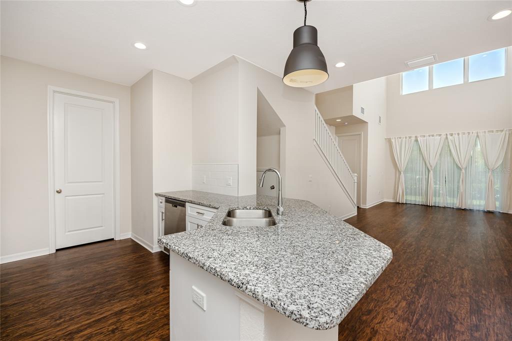 A kitchen island with granite countertops sits in an open-concept room with dark wood flooring — 1510 FIGLEAF LANE, CLEARWATER, FL