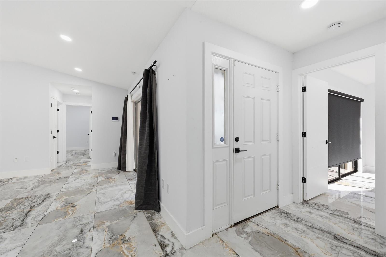 An entryway with white walls, marble-patterned tile flooring, and a white front door — 1701 Mariners Cove, Fort Pierce FL 34950, FORT PIERCE, FL