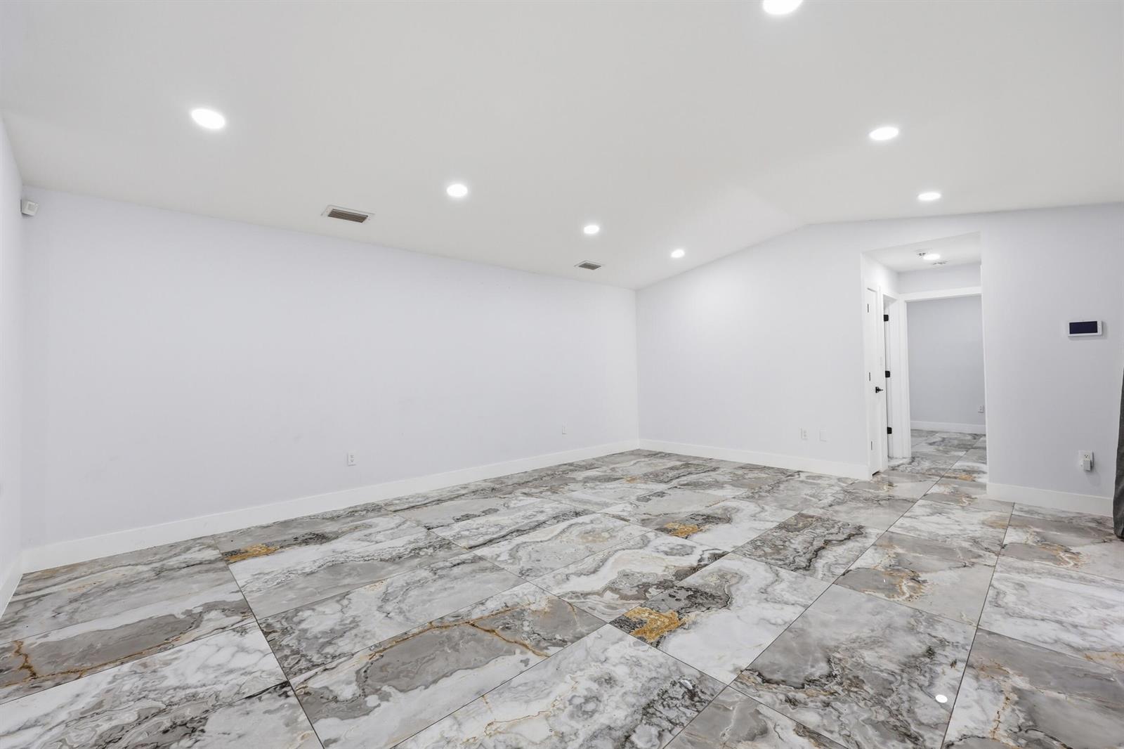 An empty room features white walls, recessed lighting, and large-format marble-patterned floor tiles — 1701 Mariners Cove, Fort Pierce FL 34950, FORT PIERCE, FL