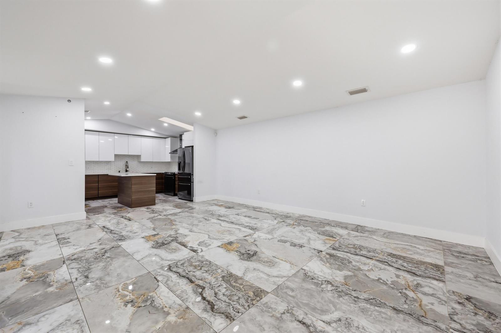 An open-concept kitchen and living area features white walls and large, patterned marble-look floor tiles — 1701 Mariners Cove, Fort Pierce FL 34950, FORT PIERCE, FL