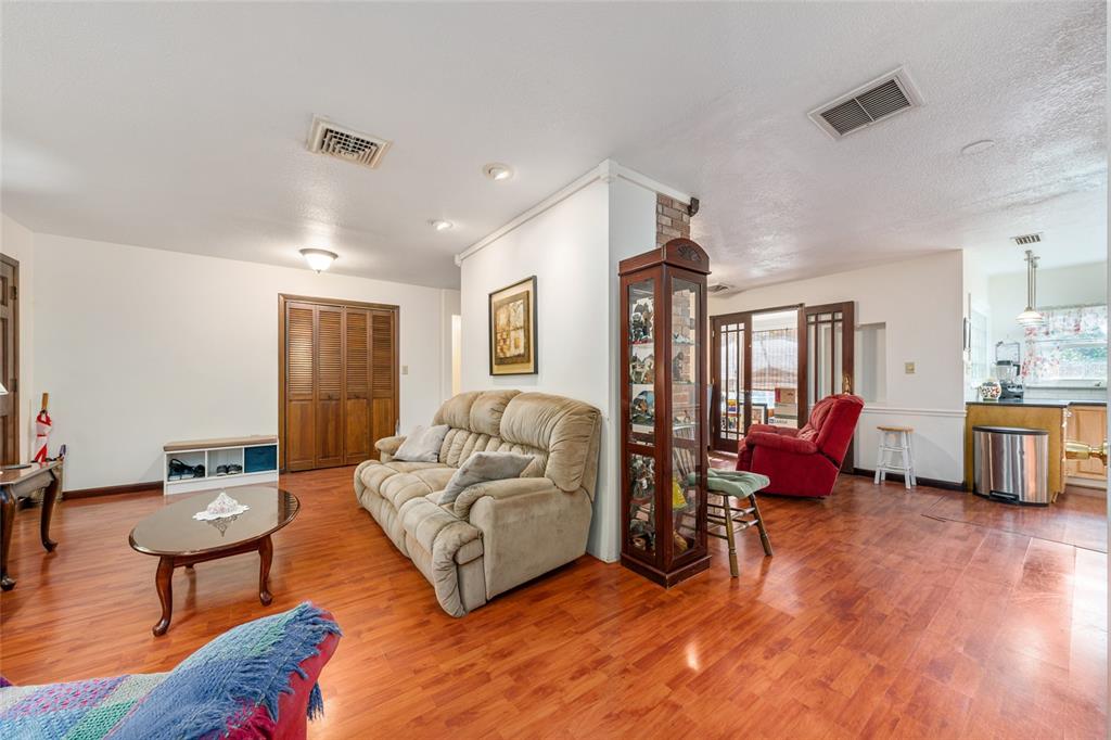 A living room with wood-look flooring, a beige sofa, a display cabinet, and a kitchen — 1008 S MILDRED AVENUE, BROOKSVILLE, FL