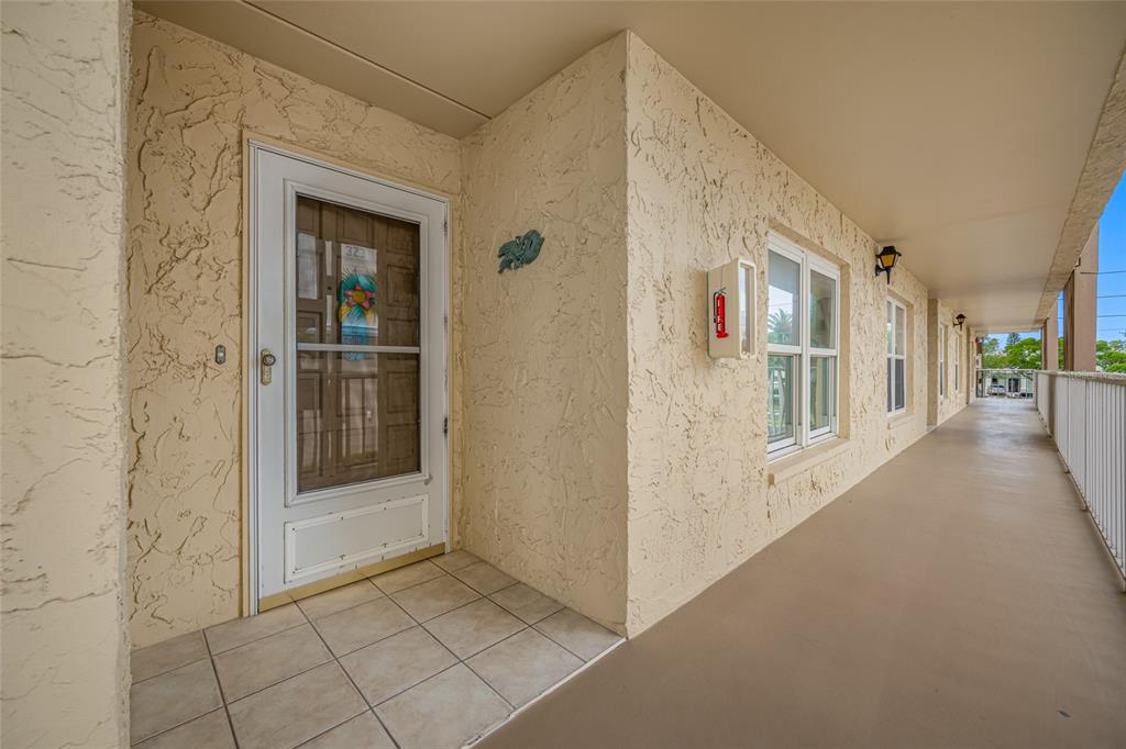 A covered exterior walkway leads to the front door of a tan stucco apartment unit — 121 ISLAND WAY UNIT 323, CLEARWATER BEACH, FL