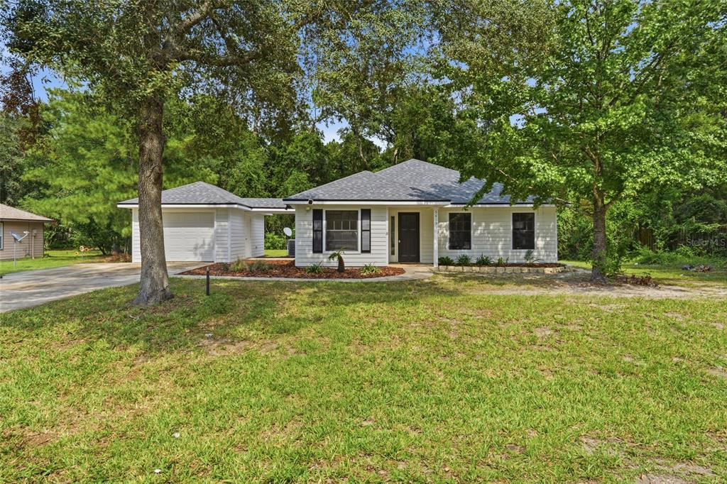 A white single-story house with a detached garage and a covered walkway sits on grass — 5813 SE 230TH TERRACE, HAWTHORNE, FL