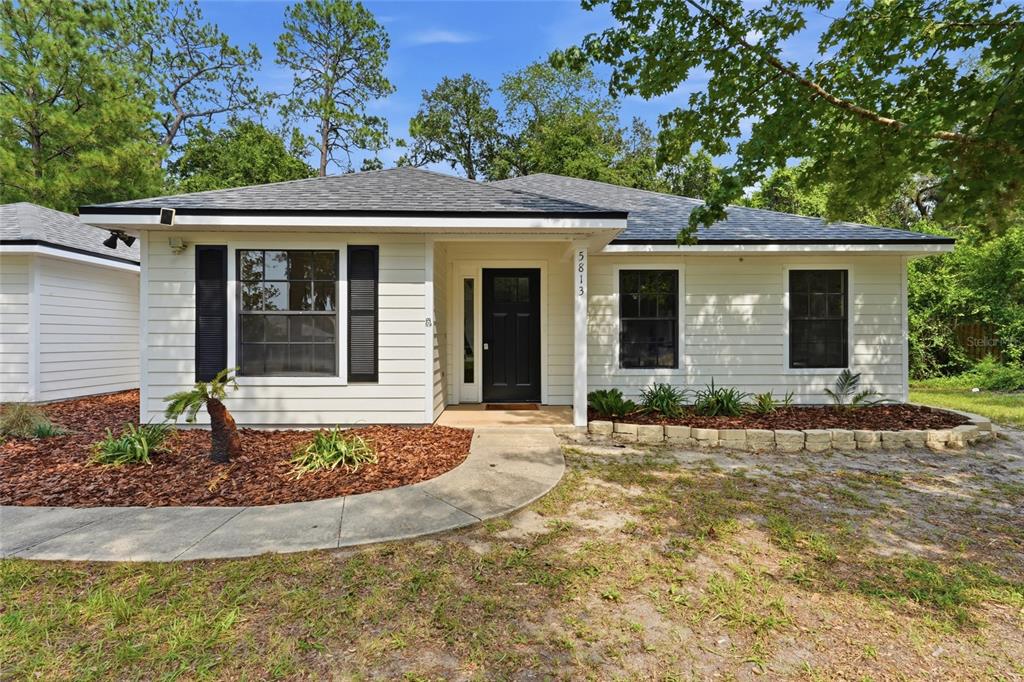 A single-story house with white horizontal siding, a black front door, and a shingled roof — 5813 SE 230TH TERRACE, HAWTHORNE, FL
