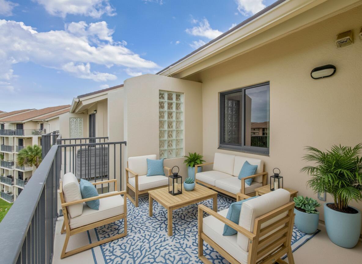A furnished balcony with a coral-patterned rug, seating area, and glass block wall — 601 Seafarer Circle # 504, Jupiter FL 33477, JUPITER, FL
