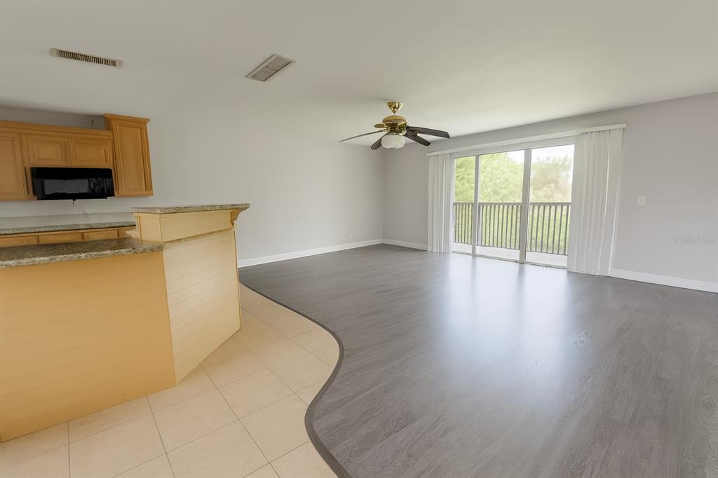 An open-concept living area features a kitchen island, tile flooring, and wood-look laminate flooring — 200 COUNTRY CLUB DR UNIT 1302, LARGO, FL