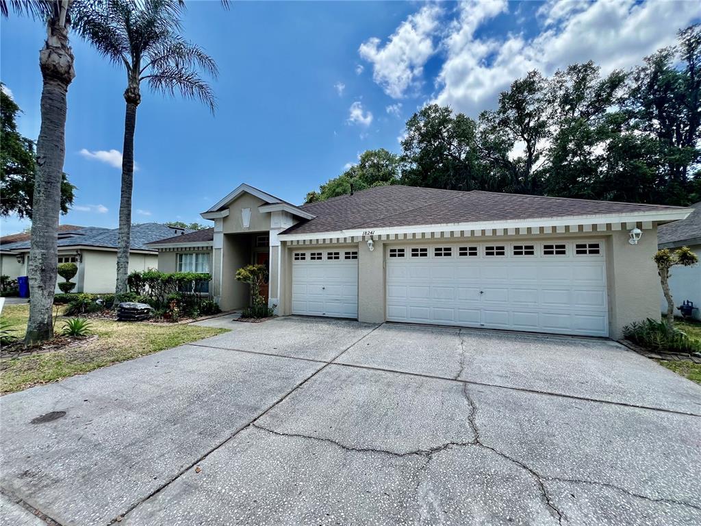 A tan single-story house with a three-car garage and a concrete driveway — 18241 COLLRIDGE DRIVE, TAMPA, FL