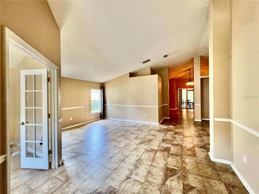 An open-concept living area features vaulted ceilings, beige walls with chair rail molding, and tile flooring — 18241 COLLRIDGE DRIVE, TAMPA, FL