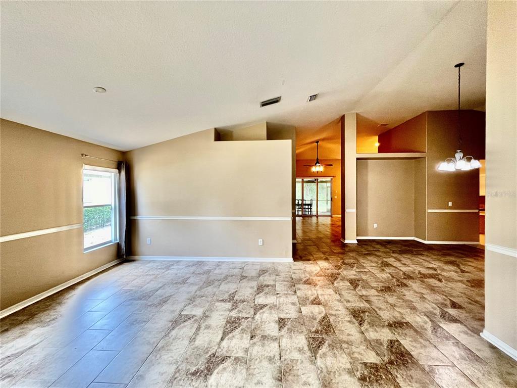 A spacious living area features beige walls, chair rail molding, and large, mottled floor tiles — 18241 COLLRIDGE DRIVE, TAMPA, FL